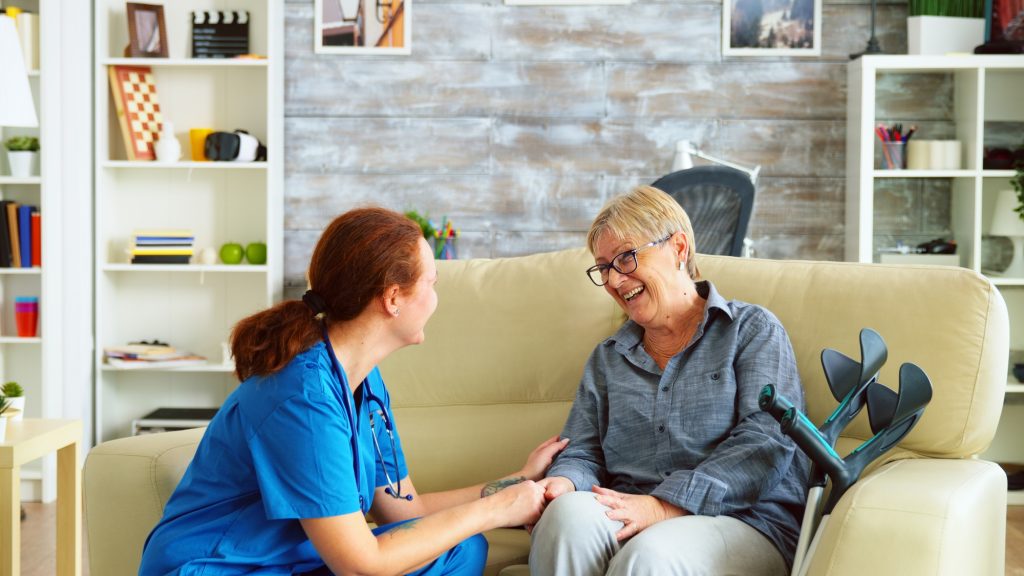 Female nurse talking with old woman with dementia